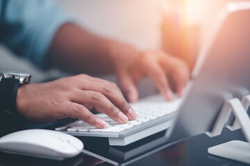 Close-up of a business man's hands working on a laptop computer while sitting at an office desk.
