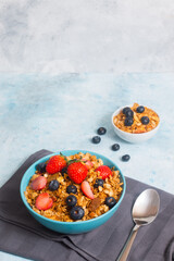 A bowl of mixed berries cereal and a small bowl of cereal with blueberries at the background