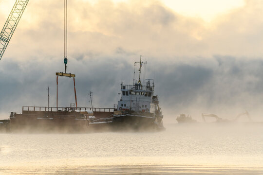 Tug moored to bardge. Strong fog in Arctic sea. Construction Marine offshore works. Dam building, crane, barge, dredger.