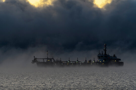 Vessel restricted in her ability to manoeuvre under way using engine at night time. Vessel engaged in dredging. Dredger working at sea. Collision regulations.