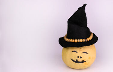 One funny pumpkin in a black witch hat and on a gray background. Halloween concept. Copy space.