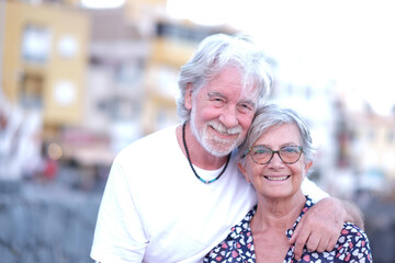Portrait of youthful senior couple embracing in outdoor at sunset light. Caucasian white haired people enjoying relax and freedom