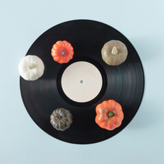 Vintage black vinyl record with colorful pumpkins on a pastel blue background. Creative retro party...