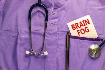 Medical and COVID-19 Pandemic Coronavirus brain fog symbol. Medical uniform, white card with words 'brain fog'. Beautiful white background. Copy space. Medical and covid-19 brain fog concept.