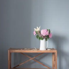 summer flowers in white jug on wooden shelf