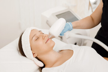 Obraz na płótnie Canvas Young woman having laser hair removal procedure of face zone by specialist in cosmetic center. Removes pigmentation in cosmetic clinic. Intensive Pulsed Light Therapy. Anti-aging treatments.