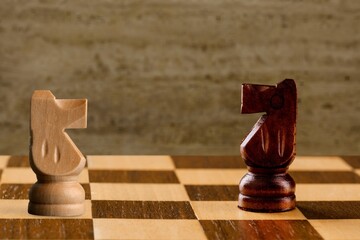 Wooden chess pieces facing each other on a vintage chessboard. Rivalry concept,