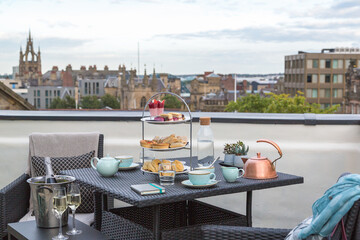 An elegant champagne afternoon tea served on a rooftop balcony overlooking the city