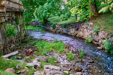 The river flows through the old town with rocky banks with the green plants
