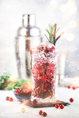 Winter alcoholic cocktail with red cranberry berries, liquor, gin, rosemary and vodka for Christmas or New Year celebration. Holiday table setting