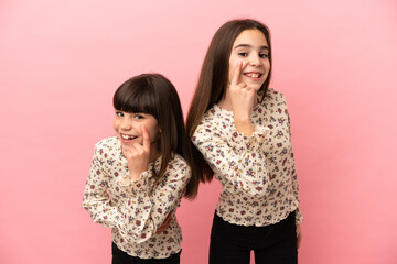 Little sisters girls isolated on pink background looking to the front