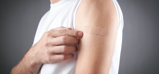 Caucasian man shows his shoulder with a bandage after vaccination.