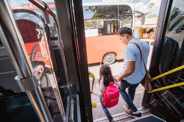 Naklejka premium asian father taking his daughter to school by riding bus public transport