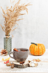 Tea with spices, anise and cinnamon on the wooden stand with pumpkin and dry grass at the background