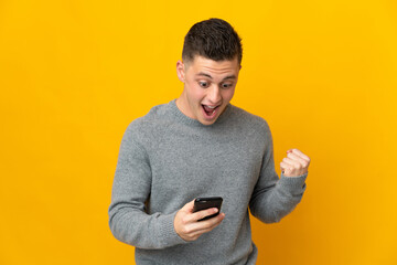 Young caucasian man isolated on yellow background surprised and sending a message