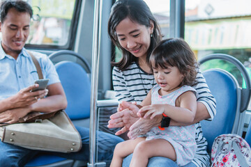 happy asian mother taking her daughter riding public transport