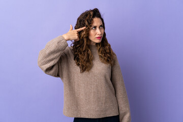 Young caucasian woman isolated on purple background making the gesture of madness putting finger on the head