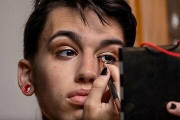 Young transgender woman putting on her eyes. Daily life