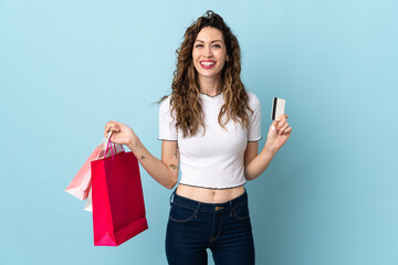 Young caucasian woman isolated on blue background holding shopping bags and a credit card