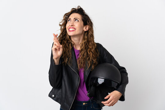 Young caucasian woman holding a motorcycle helmet with fingers crossing and wishing the best