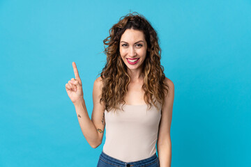 Young caucasian woman isolated on blue background pointing up a great idea