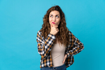 Fototapeta premium Young caucasian woman isolated on blue background having doubts and with confuse face expression
