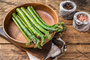 Asparagus uncooked in a wooden plate board. wooden background. Top view