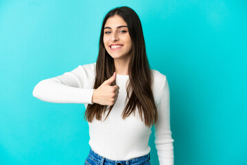 Young caucasian woman isolated on blue background giving a thumbs up gesture