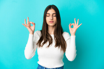 Young caucasian woman isolated on blue background in zen pose