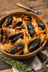 Mussels and clams Mafaldine pasta with tomato sauce in a rustic wooden plate. Wooden background. Top view