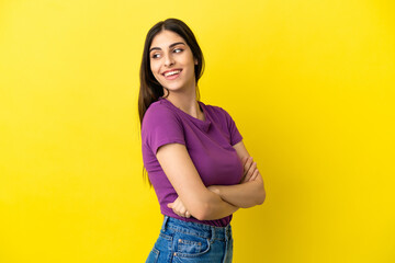 Young caucasian woman isolated on yellow background with arms crossed and happy