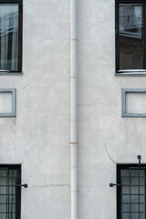 Obraz premium An unusual facade of an office building. Narrow non-standard windows form an amazing recognizable style. A drainpipe spoils the beautiful style of an old building