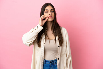 Young caucasian woman isolated on pink background showing a sign of silence gesture