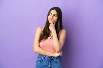 Young caucasian woman isolated on purple background having doubts