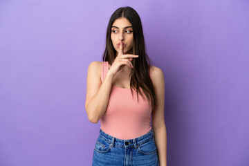 Young caucasian woman isolated on purple background showing a sign of silence gesture putting finger in mouth