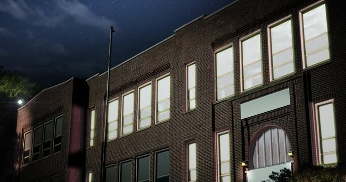 A night establishing shot of a typical small town two-story red brick school building. Room lights turn on and off. Day version available.	