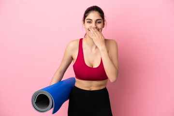 Young sport caucasian woman going to yoga classes while holding a mat happy and smiling covering mouth with hand