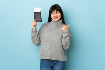 Young Ukrainian woman isolated on blue background in vacation holding a passport and plane with thumb up