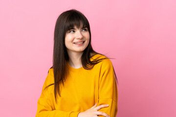 Fototapeta premium Young Ukrainian woman isolated on pink background looking up while smiling