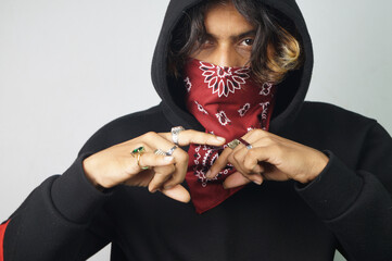 Young thug Indian male with a bandana covering his face doing gang signs