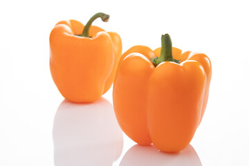 Two orange bell peppers isolated on white background, one of them is out of focus, bokeh