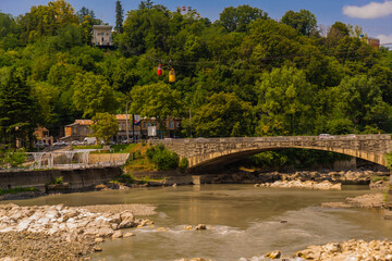 Fototapeta na wymiar KUTAISI, GEORGIA: The Cable Car passes over the Shota Rustaveli Bridge and the Rioni River.