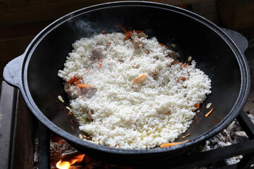 Cooking pilaf in cauldron on fire in gazebo