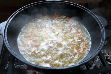 View of cooking pilaf in cauldron on fire