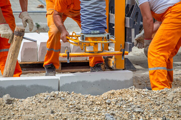 Workers using machine to set the concrete curb