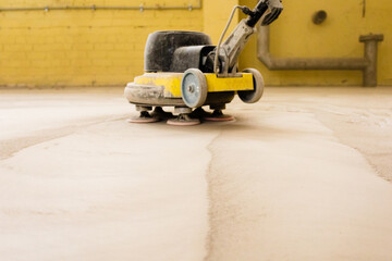 Concrete floor grinding. Construction process. Sanding a concrete floor with a sander in a warehouse