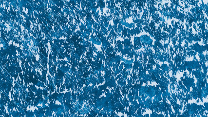 Blue ice surface with scratches and snow