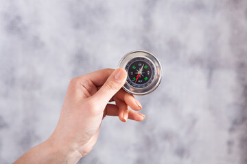 hand holds compass on gray background