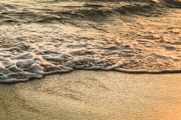 Waves and sand texture on the beach at sunset