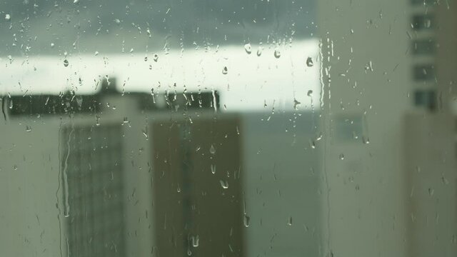 Close-up of water droplets on glass, Rain Rain, Go Away. Large rain drops strike a window pane during a summer shower. 4K.